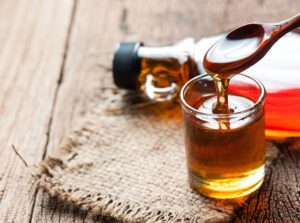 Fresh maple syrup dripping from a wooden spoon.