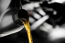 Manufacturer-recommended oil is poured from a plastic jug into a vacuum pump.